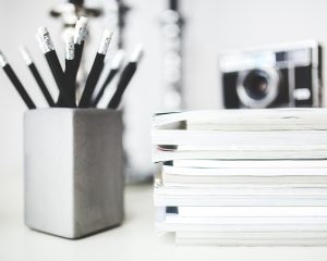 桌面角落的牛皮纸信封与一支铅笔，信封上用铅笔写着标签编号，背景是虚化的书架
