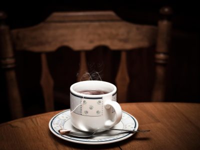 窗边书桌上的一杯热茶与笔记本，屏幕反光里隐约可见检索框
